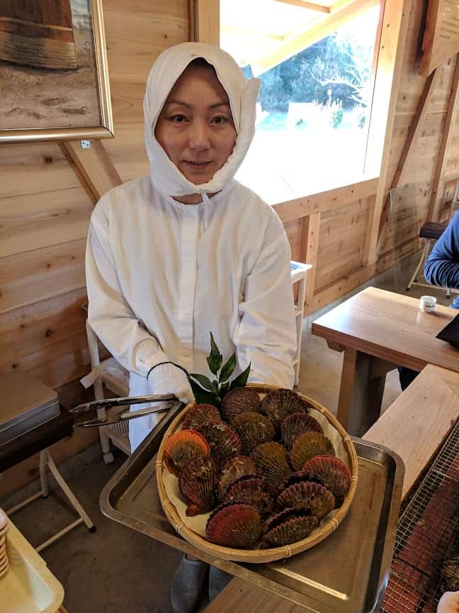 Ama in white clothing selling shellfish.