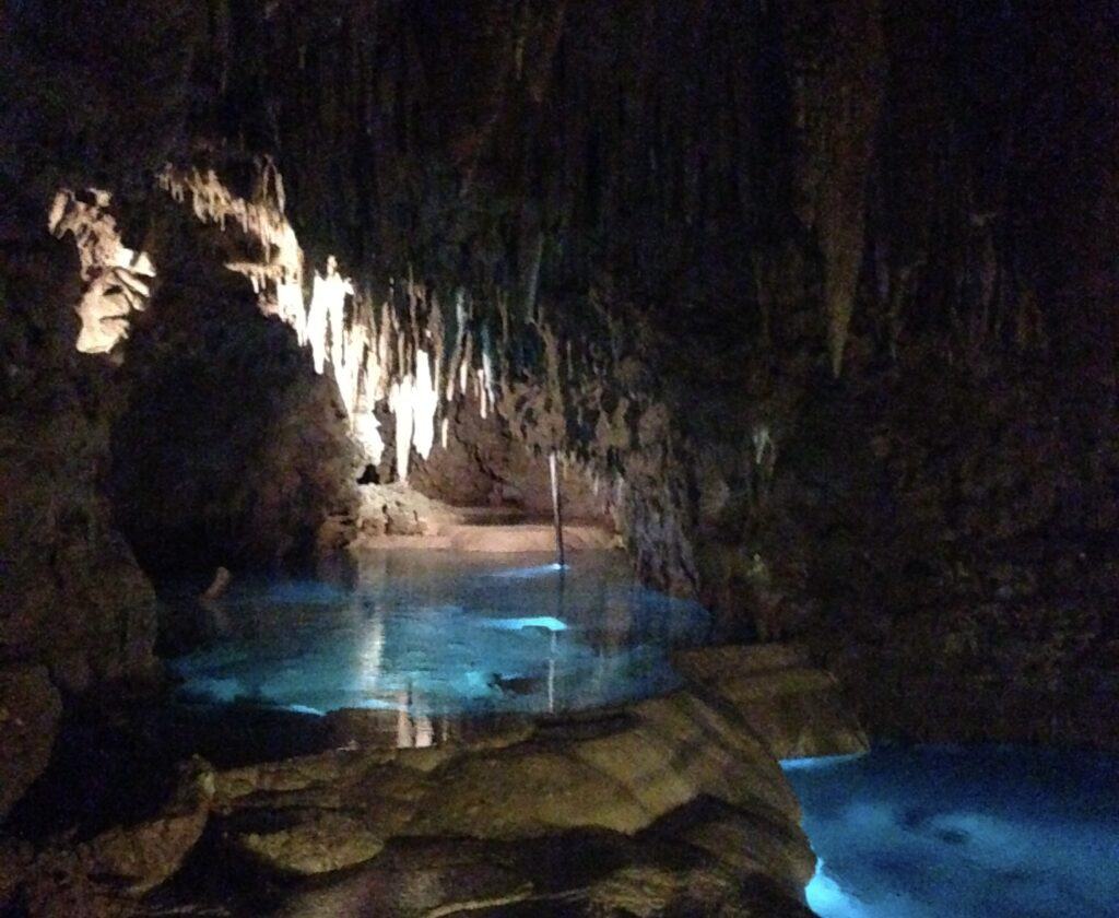 Blue waters inside a cave hung with stalactites. 