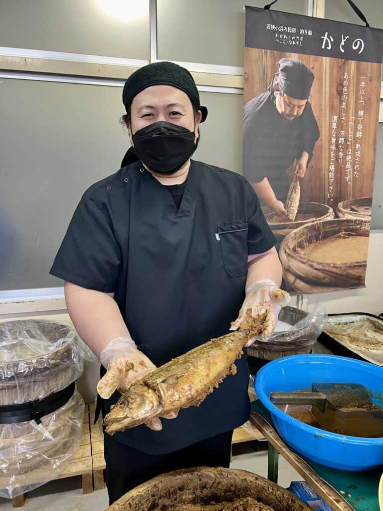 Kadono-san, who makes heshiko, holds a mackerel that is being fermented with rice bran and koji mold.