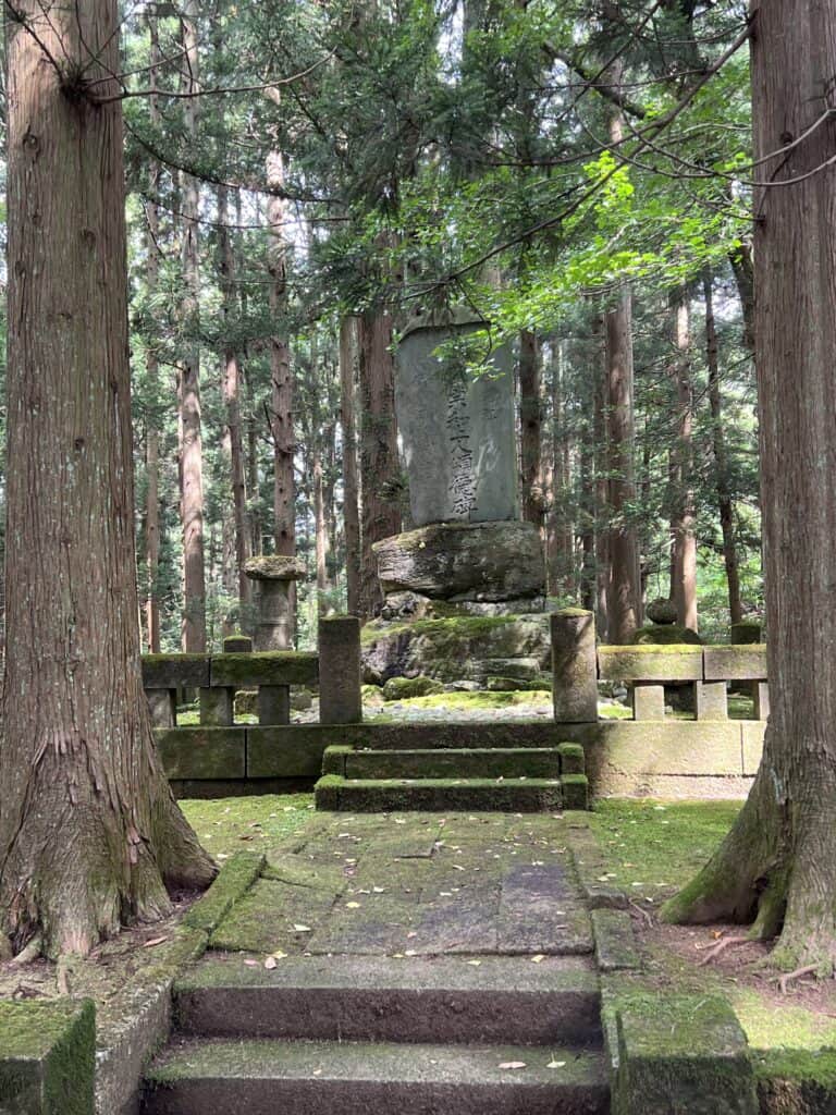 Stone monument on a raised area in a forest.