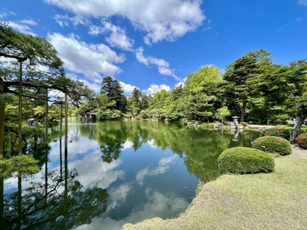 Glassy waters surrounded by lush greenery reflect the brilliant blue of the sky and cottony clouds.