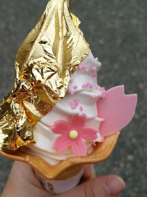 Soft serve ice cream covered with gold leaf and cherry blossom shaped sweets.